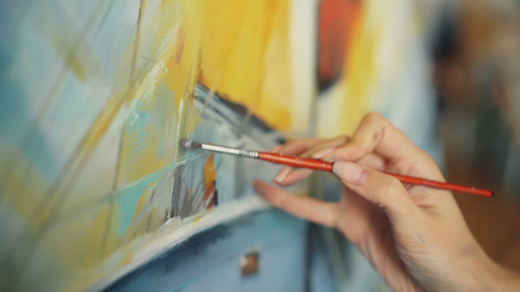 A hand painting a canvas in an art studio.